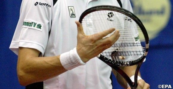 Denmark's Kenneth Carlsen inspects his racket during the match against  Thailand's Paradorn Srichaphan